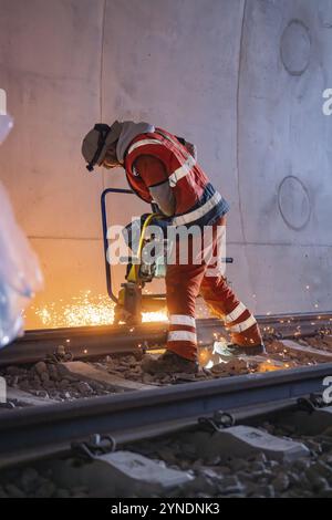 Un lavoratore che smeriglia le rotaie in un tunnel, spruzzatura di scintille, saldatura di rotaie, costruzione di binari Hermann Hessebahn, Calw, Foresta Nera, Germania, Europa Foto Stock