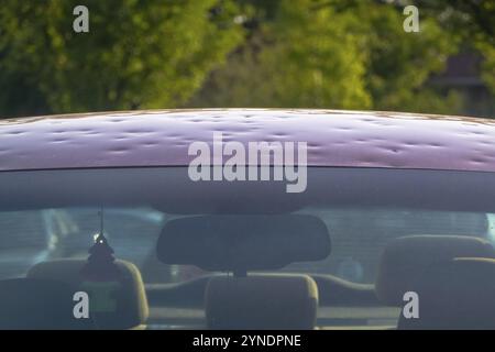 Calgary, Alberta, Canada. 12 luglio 2024. Un primo piano di un'auto con danni dovuti alla grandine e parabrezza incrinato con il cofano ammaccato Foto Stock