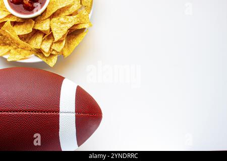 Un calcio americano con chip nacho organici e salsa dolce sul lato su uno sfondo bianco Foto Stock