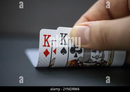 Calgary, Alberta, Canada. 18 dicembre 2023. Una persona che guarda le carte del Re di partenza durante una partita di poker. Concetto: Le grandi coppie dei mostri Foto Stock