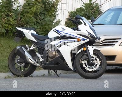 Calgary, Alberta, Canada. 21 luglio 2024. Un'elegante moto bianca Honda CBR500R parcheggiata accanto a un'auto Foto Stock