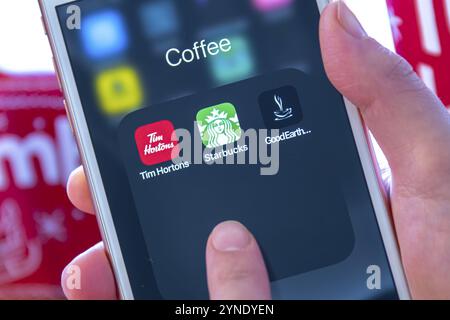 Calgary, Alberta. Canada dicembre 28 2019. Una persona che ha in mano un iPhone con app per caffè di Tim Hortons, Starbucks e Good Earth Foto Stock