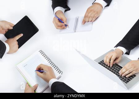 Mani di uomini d'affari durante una riunione di lavoro. Prendere appunti, utilizzando un tablet e un notebook Foto Stock