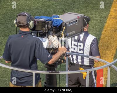 Calgary, Alberta, Canada. 21 luglio 2024. Un cameraman filma un evento sportivo a margine, accompagnato da un arbitro che indossa una maglia a strisce Foto Stock