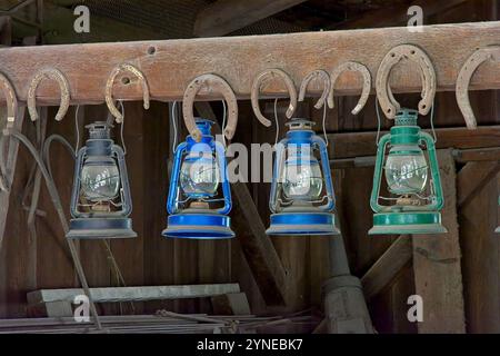 Fila di antiche lanterne a olio appese nel vecchio fienile Foto Stock