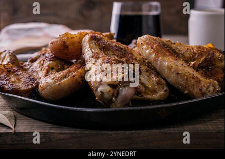 Ali di pollo marinate speziate fatte in casa e patate fritte su piatto rustico e tavolo in legno Foto Stock
