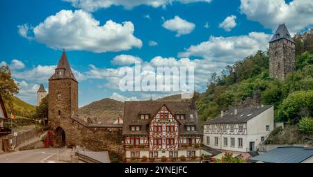 Cancello medievale restaurato della città e mura della città, case per metà in legno nell'alta valle del Medio Reno a Bacharach, in Germania, cielo nuvoloso blu Foto Stock