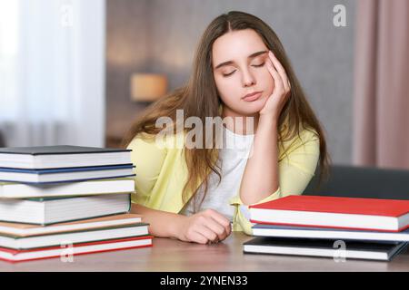 Giovane studente con libri che hanno stress prima dell'esame al tavolo di legno Foto Stock