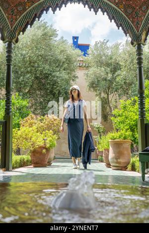 Giovane donna dai capelli scuri in tuta blu navy e berretto bianco al Secret Garden di Marrakech, Marocco Foto Stock