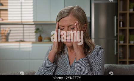 Malsano anziano maturo turbato stanco donna caucasica nonna soffre di mal di testa tenendo templi testa sensazione di dolore affaticato soffre Foto Stock