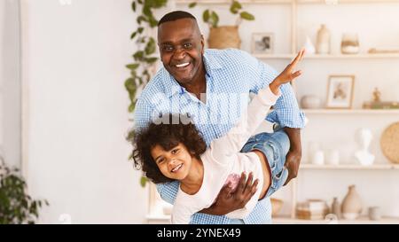 Divertimento in famiglia. Felice nonno afroamericano che gioca a stupido gioco con sua nipote a casa, spazio vuoto Foto Stock