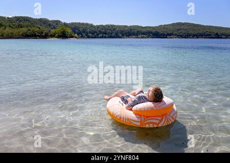 Un ragazzo che si rilassa galleggiando sul lago McKenzie, Boorangoora, l'isola K'gari Fraser, destinazione di viaggio per le vacanze, Queensland Australia Foto Stock