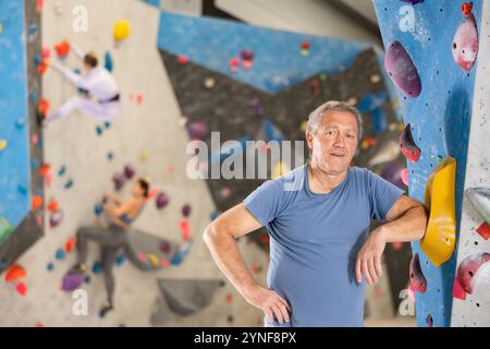 Un uomo anziano sicuro di sé in piedi nel centro sportivo di arrampicata Foto Stock