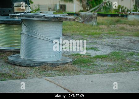 Grande bobina di filo in legno al suolo all'interno di una sottostazione elettrica vicino a Sunset in Florida altri materiali, pali di erba verde sul retro Foto Stock