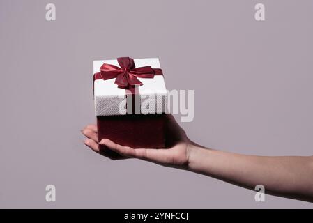 Confezione regalo a mano, sorpresa e concetto di vacanza. Regalo di San Valentino. Donna con le mani in mano una scatola regalo rosa. Ragazza con una confezione regalo. Mani di donna Foto Stock