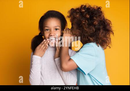 Una ragazza carina che racconta il segreto della sua amica sullo sfondo Foto Stock