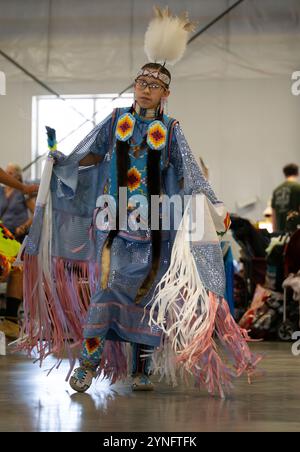 Giovane donna nativa americana che indossa un costume di scialle rosa e lavanda che danza in un pow wow a Helena, Montana. Foto Stock