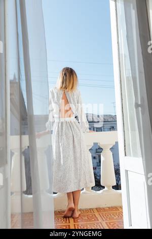 Bella donna in vestaglia sul balcone con la schiena Foto Stock