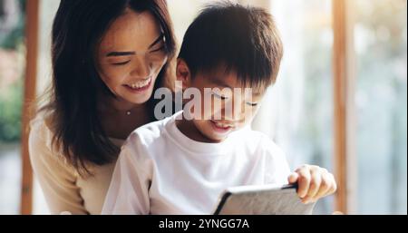 Madre, figlio e tablet a casa per legare, giocare ai videogame o riprodurre video dei cartoni animati in streaming con Internet. Famiglia giapponese, ragazzo e mamma insieme Foto Stock