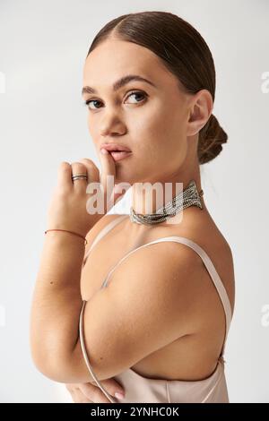 Una giovane donna di statura corta si posa con eleganza in un abito elegante, sfoggiando lo stile. Foto Stock