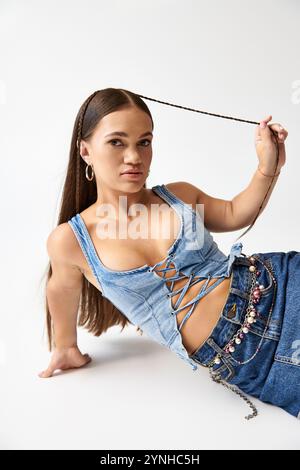 Una giovane donna alla moda con una statura corta indossa con sicurezza un abbigliamento in denim. Foto Stock