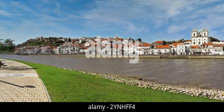 Vista sul lungomare di Alcacer do Sal dall'altra parte del fiume Sado con la chiesa di Santiago sulla destra e il castello sulla sinistra Foto Stock