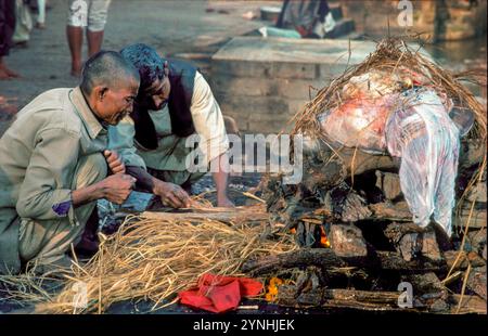 India, Varanasi, Benares, cremazione rituale sul Manikarnika Ghat sul fiume Gange. I membri della famiglia eseguono il rituale con il legno che hanno comprato. Foto Stock