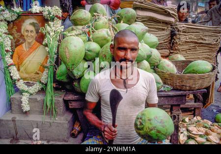 India, Madras/Chennai, venditore di noci di cocco con un ritratto dell'ex primo ministro Indira Gandhi. Foto Stock