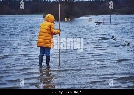 Donna che controlla l'acqua in un'inondazione nel villaggio polacco Foto Stock