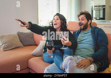Un momento naturale di coppia giovane che si gode una serata di intrattenimento. Autentica emozione e reazione spontanea mentre condividi momenti rilassanti su sof Foto Stock