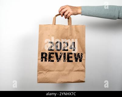 2024 revisione. A portata di mano un sacchetto per la spesa di carta su sfondo bianco. Foto Stock