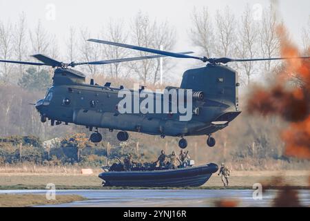 Un potente elicottero Chinook sorvola con precisione su una barca tattica ad alta velocità mentre i soldati eseguono un'operazione di spiegamento sincronizzata. La scena c Foto Stock