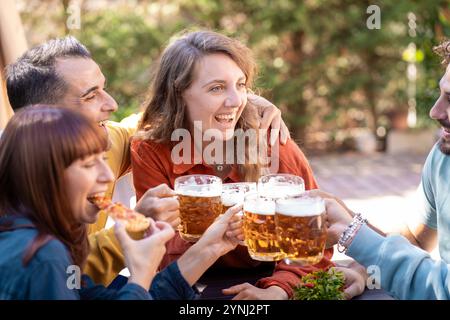 Interazione naturale di gruppo durante un incontro informale con la birra in giardino. Un momento di amicizia genuina che cattura le risate spontanee e le connessioni reali Foto Stock