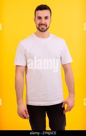 Ritratto di un uomo sorridente con t-shirt bianca su sfondo giallo. Verticale Foto Stock