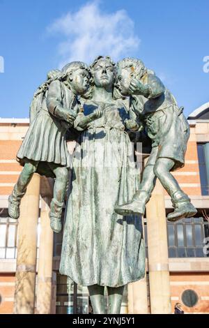 Statua raffigurante scale di giustizia con donna che tiene in braccio due bambini litiganti, situata di fronte a una corte della corona di middlesbrough sotto un cielo azzurro Foto Stock