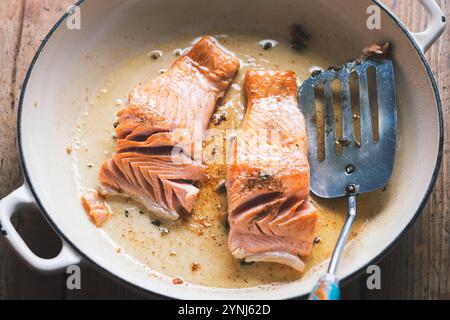 Salmone fritto con olio sulla padella Foto Stock