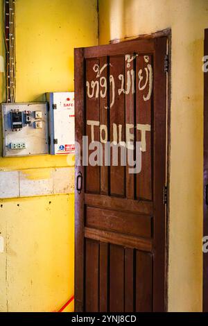 Insegna dipinta a mano sulla porta di legno di un bagno a Vang Vieng, nel Laos settentrionale, nel sud-est asiatico Foto Stock