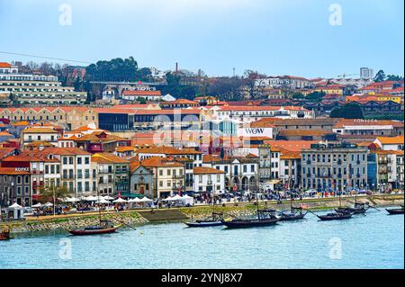 Porto, Portogallo - 17 luglio 2024: Vista ad alto angolo del paesaggio urbano sul fiume Douro, con un gruppo di barche rabelo ormeggiate sulla riva del fiume. Foto Stock