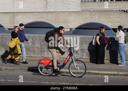 Un uomo che attraversa il Waterloo Bridge, su un Transport for London Santander Cycles, noleggia una bicicletta, comunemente nota come “Boris Bike”. Waterloo Bridge, L. Foto Stock