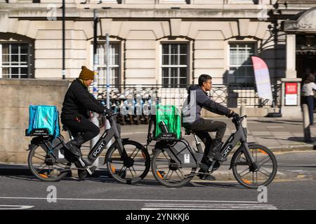 Un corriere ciclistico Deliveroo e Uber Eat in sella a una e-bike attraverso Waterloo Bridge, Londra, Regno Unito. 11 ottobre 2024 Foto Stock