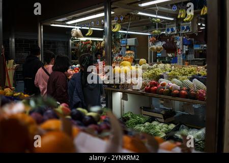 Bologna, Italia. 8 ottobre 2024 - i clienti esplorano un mercato di frutta in serata al mercato delle Erbe. Foto Stock