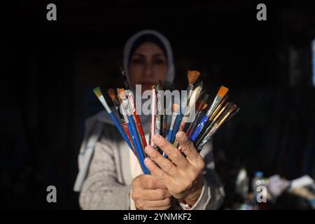 L'artista palestinese Maysaa Youssef, 38 anni, dipinge tra le macerie della sua casa, distrutta dai bombardamenti israeliani a Deir al-Balah, il 26 novembre 2024, nel mezzo della guerra in corso nei territori palestinesi tra Israele e Hamas. (Foto di Majdi Fathi/NurPhoto) credito: NurPhoto SRL/Alamy Live News Foto Stock