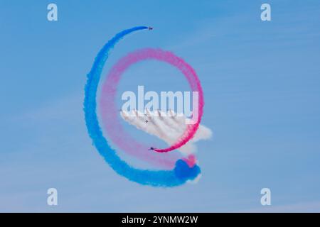 Le frecce rosse eseguono una manovra aerobica mozzafiato, creando piste di fumo rosse, bianche e blu intrecciate contro un cielo limpido. Questa dinamica e. Foto Stock