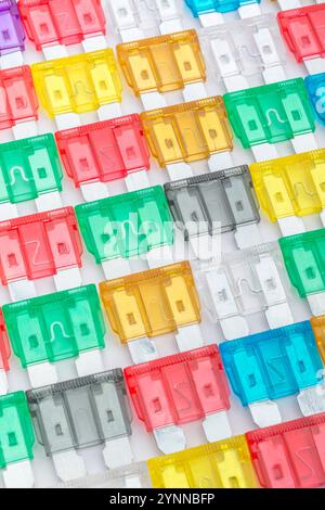 Massa ordinata di fusibili colorati per auto plug-in per uso automobilistico con vari codici colore di amperaggio. Metafora diversità, scelta. Foto Stock