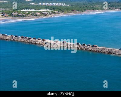 Molti camion caricano con pietre sulla costruzione di spiagge oceaniche con vista aerea su droni Foto Stock