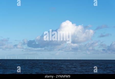 Nuvola bianca e cielo blu sul parco eolico offshore Gwynt y Môr all'orizzonte nel Mare d'Irlanda vicino a Llandudno, Galles. Foto Stock