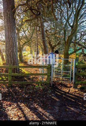 Un uomo in spalla che cammina attraverso un cancello per baciare che si snoda lungo il Sandstone Trail, un sentiero di 34 km attraverso la campagna del Cheshire Foto Stock