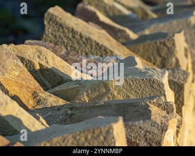 Primo piano delle pietre di arenaria che ricoprono la parte superiore di un muro di pietra secca, bagnate dal sole dopo una gelata. Foto Stock