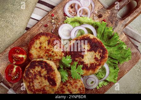 Cotolette di pollo fritte, pollo tritato, con verdure, su un tagliere, con insalata di verdure, vista dall'alto, fatti in casa, nessuno Foto Stock