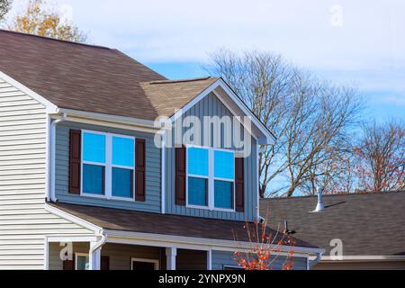 La bella casa a due piani presenta grandi finestre incorniciate da persiane di legno caratterizzate da un ambiente periferico Foto Stock
